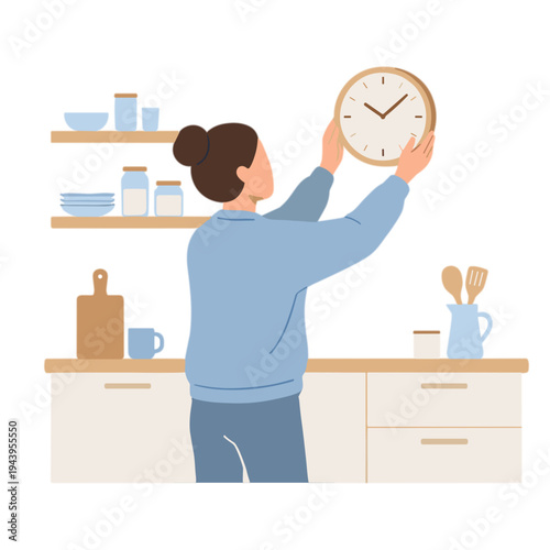 Woman hanging clock on kitchen wall near shelves and cabinets