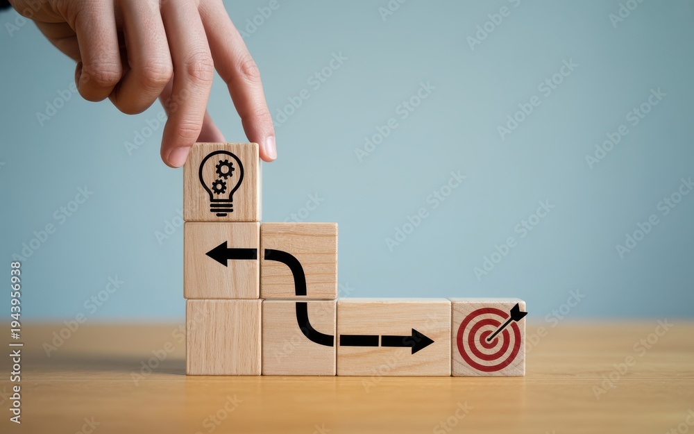 © Habiba Noor Jannat - Hand placing wooden block with lightbulb icon on a path leading to a target for business strategy concept © Habiba Noor Jannat - Hand placing wooden block with lightbulb icon on a path leading to a target for business strategy concept