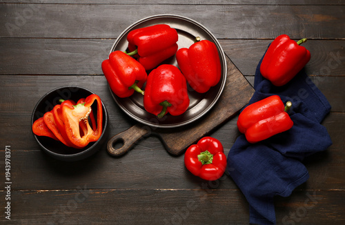 Foto Plate and bowl with red bell peppers on wooden background