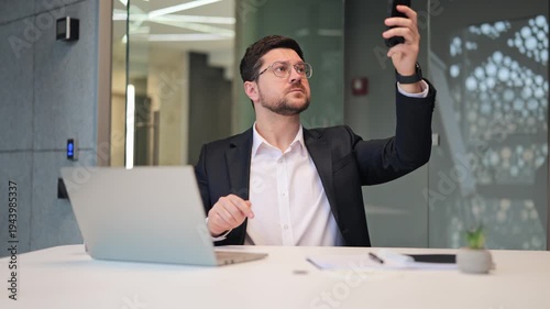 Frustrated male entrepreneur looking at smartphone in anger due to no Wi-Fi and cellular connection. Stressed businessman shouting and gesturing because of lost internet signal in the office.