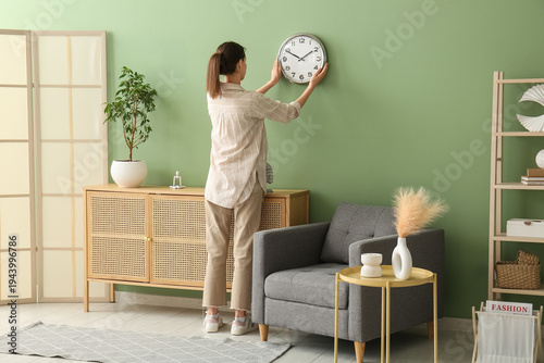 Young woman hanging clock o...