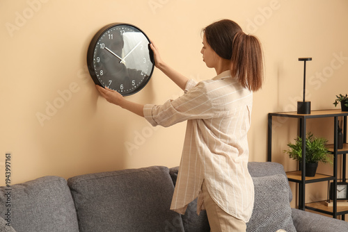 Young woman hanging clock o...