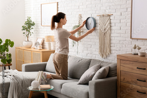 Young woman hanging clock o...