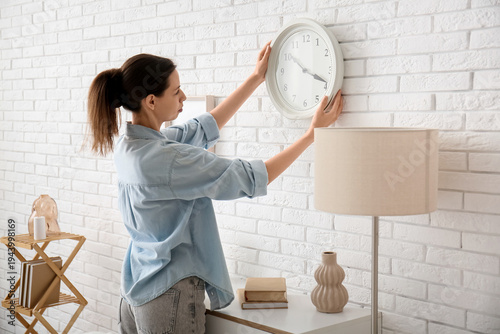 Young woman hanging clock o...