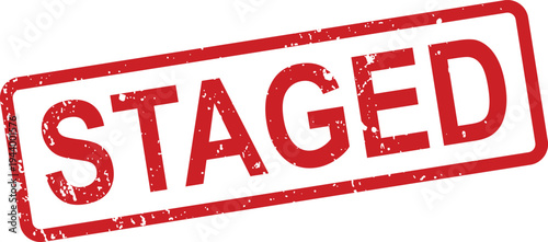 A distressed red rectangular rubber stamp clearly presents the word STAGED against a clean white backdrop