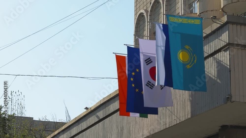 The flags of Kazakhstan, Russia, South Korea, the European Union, and India hang on the building