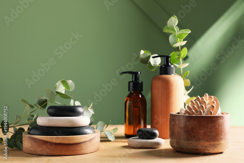 Photography Bottles of cosmetic products, spa stones and bath supplies on wooden table near