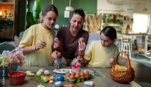 Cuadro en lienzo Mother and her two daughters engaging in a creative activity, decorating easter