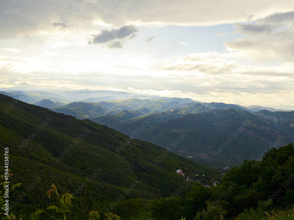Obraz premium Sunlight Over Rolling Green Mountains and Scenic Valley Landscape