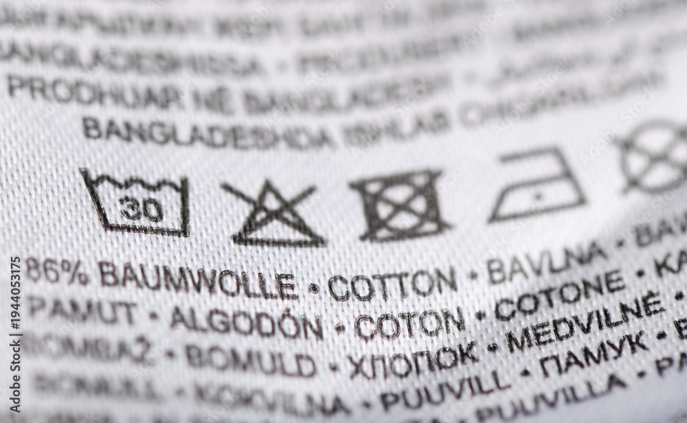 Fototapeta premium Close-up of white garment care label with laundry symbols and fabric content.