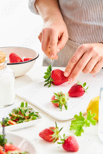 woman hands cutting off the stems of strawberries with a knife