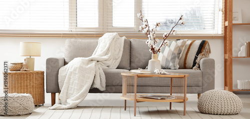 Interior of living room with grey sofa, table and cotton flowers in vase