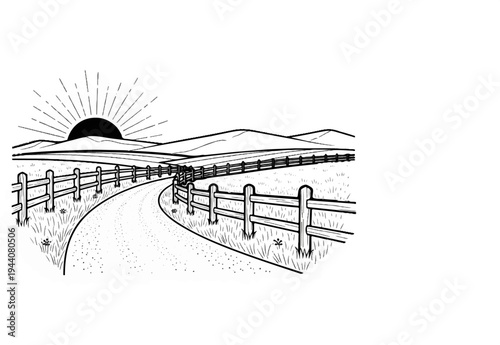 A curved dirt road leads through a grassy field towards distant hills at sunrise