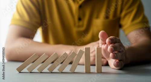 Man in yellow shirt stopping a domino effect with his hand