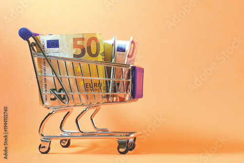 Euro banknotes of different amounts in a shopping cart, copy space. Economic concept.