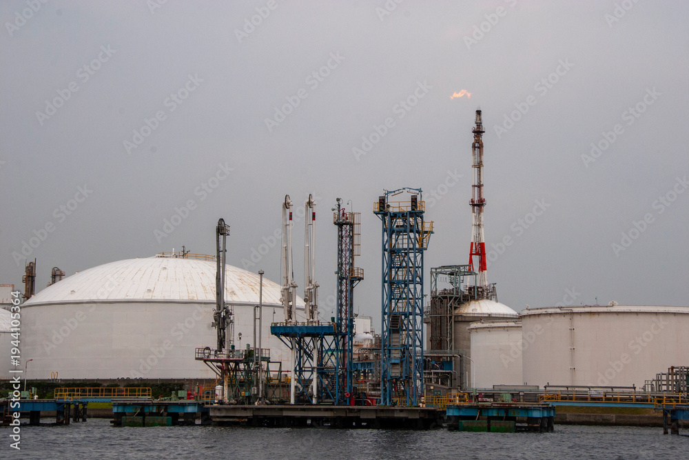 Obraz premium Oil refinery factory with flare stack and smoking chimneys at dusk
