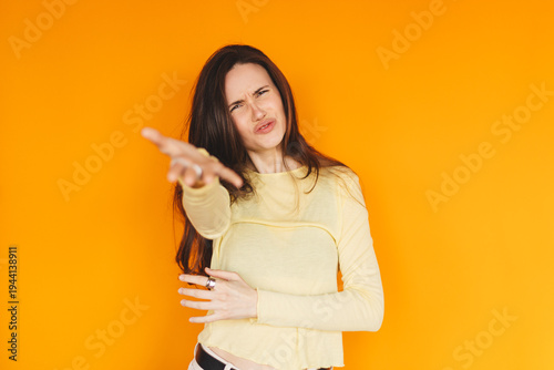 Photography Skeptical young woman pointing at camera with disbelief on orange background, an