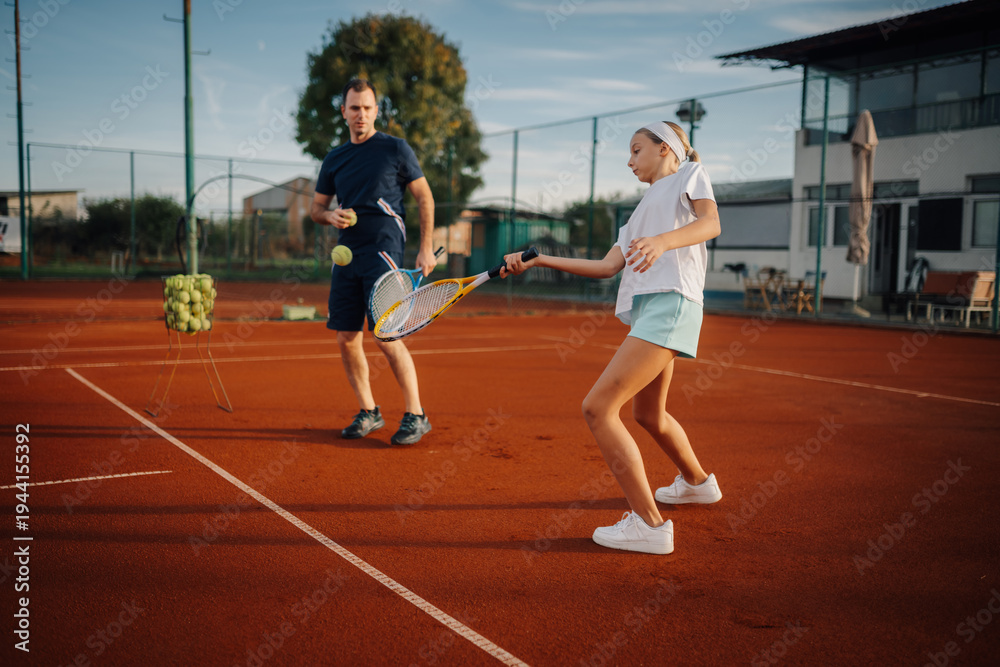 © Ljustina - Tennis coach teaching young girl forehand on clay court