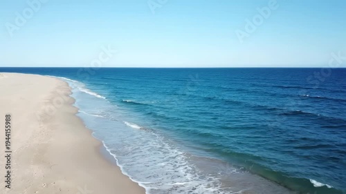 Aerial drone view long, empty sandy beach meeting deep blue ocean waves under clear summer sky, for tranquility, escape, natural beauty coastline