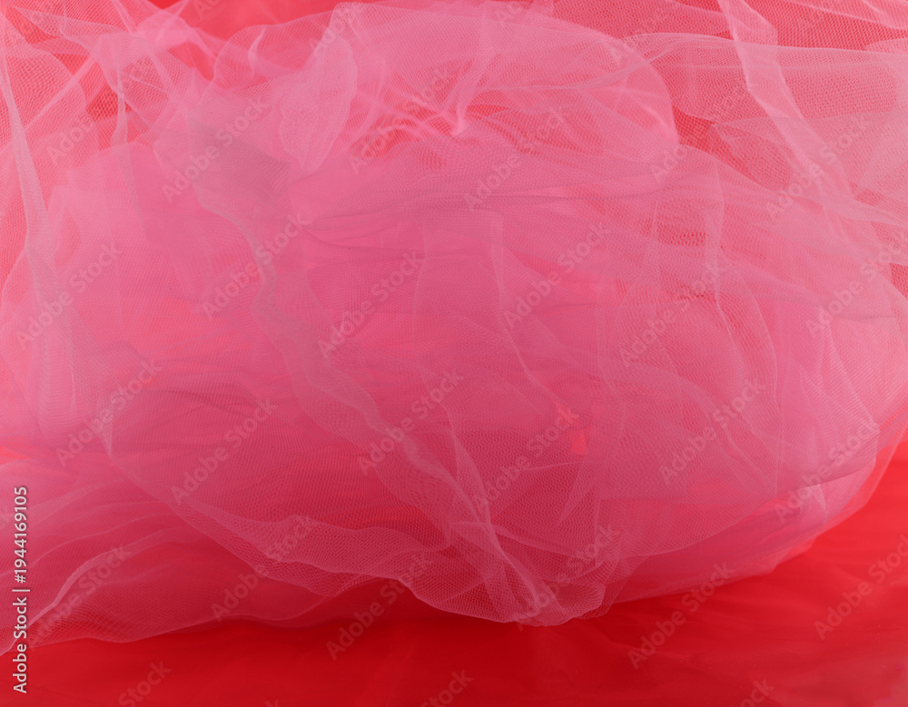 Fototapeta premium Pink tulle fabric on red background. Abstract transparent material curve wave.
