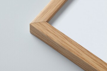 Close-up of a natural wood picture frame corner on a clean grey background.