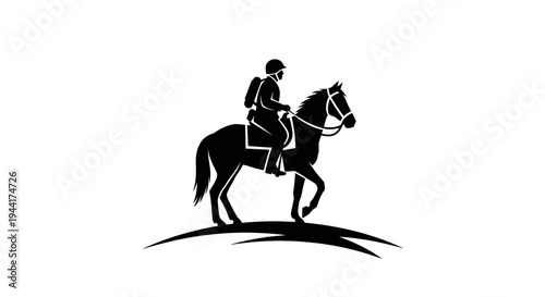 Silhouette of a jockey riding a horse on a grassy hill at sunset