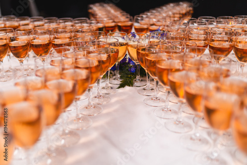 Fotografie Rows of elegant wine glasses filled with rose wine or champagne on a white tablecloth
