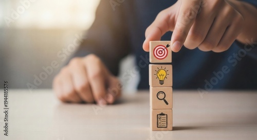 Business Goal Setting and Strategic Execution. Hand stacking target icon cube above vertical sequence of business process blocks, representing strategy, systematic workflow and goal achievement.
