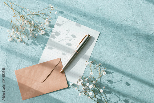 Spring message concept with envelope, pen and baby's breath flowers on blue background