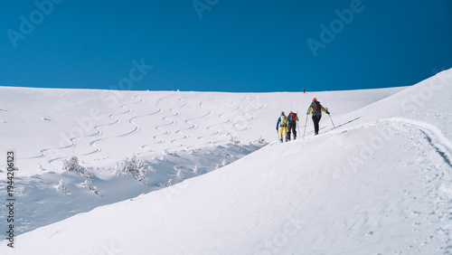 Group ski mountaineering ascending snowy mountain slope