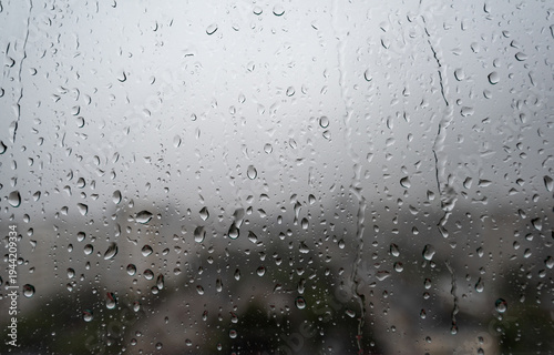 Photos Rain drops on window glass during cloudy rainy weather with blurred city view in the background