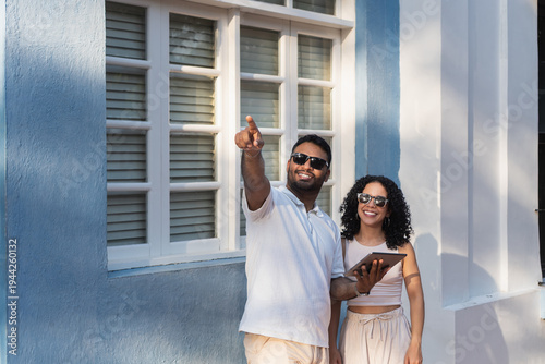 Happy couple pointing, discovering new city with digital tablet
