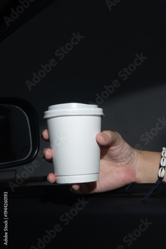 Holding Hot Coffee Cup Against Dark Car Interior