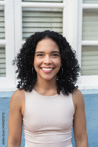 Young woman with curly hair smiling outdoors