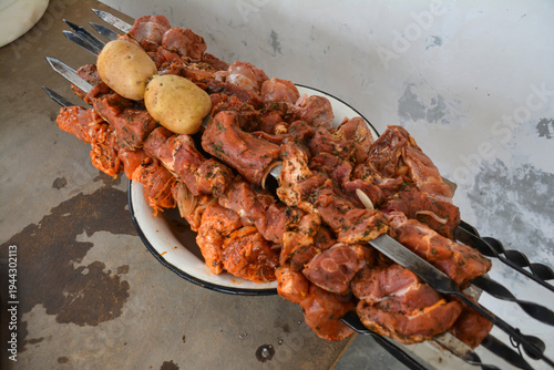 Pork shish kebab with potatoes on a metal skewer. Barbecue grilled chicken and pork on skewers with spices