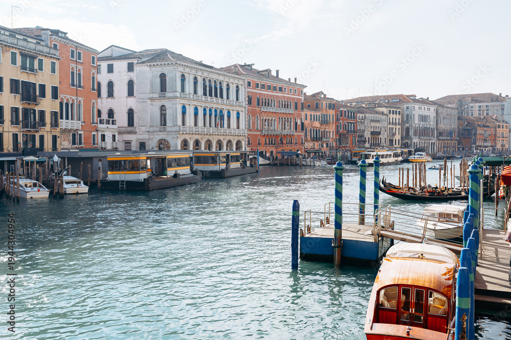 Obraz premium People walk along the canal in Venice while boats float on the water