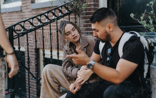 Quadro em tela A young couple sits on outdoor steps in Amsterdam having a focused conversation