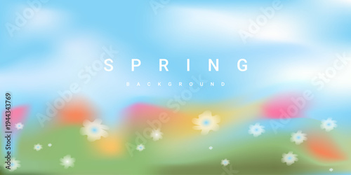 Blurred spring landscape background with soft white flowers, blue sky and green grass. Calm fresh natural scenery.