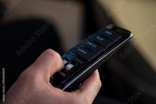 Schilderij op canvas Passenger controlling seat massage function using remote control with massage modes and intensity adjustment in luxury car interior