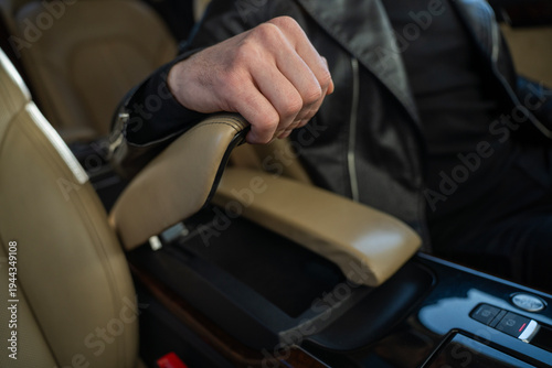 Foto Driver hand lifting adjustable center armrest on luxury car seat revealing storage compartment