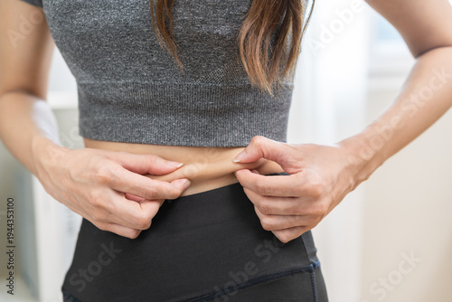 Billede på lærred Obese, obesity chubby asian young woman, girl hand holding belly, show excess fat of waist, belly