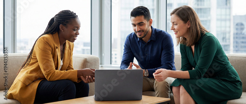 Multicultural team sitting on sofa discussing business strategy using a laptop with back side visible, modern office lounge environment.