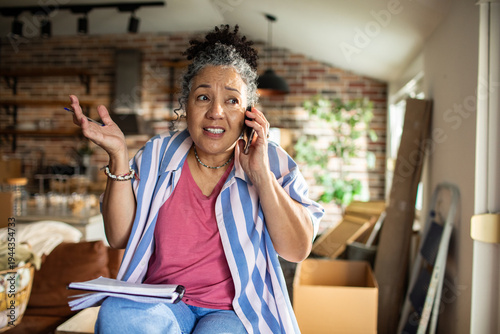 Photos Worried woman on smartphone during home renovation and moving