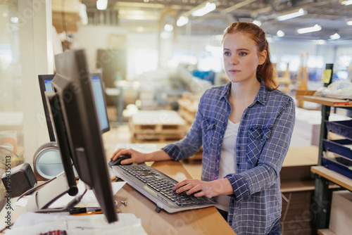 Young woman using desktop computer in warehouse office