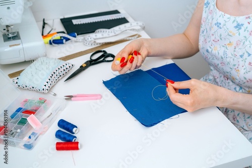Close-up of hand basting stitch on blue fabric pieces in dressmaking process