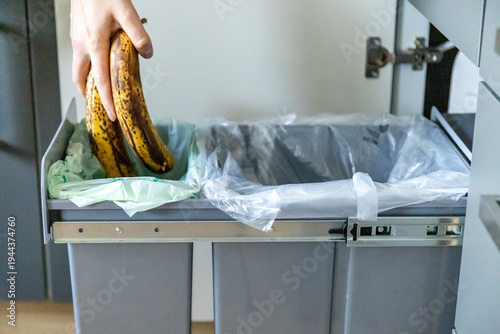 Foto A housewife throwing tainted bananas into a garbage bin in kitchen