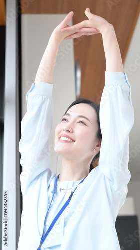 新緑の会社の窓際で伸びやストレッチする休憩するビジネスシーンの女性　スッキリして気分爽快の縦動画