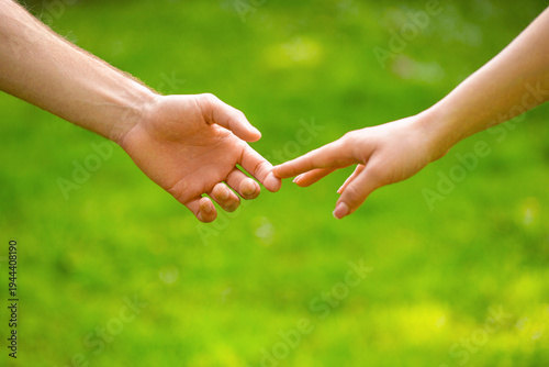 Couple hold hand in the autumn or summer park. Closeup of loving couples holding hands while walking. Young couple holding hands in grass field, outdoors. Hands, couples