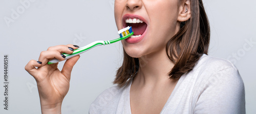 Happy girl brushing her teeth. The concept of a healthy lifestyle. Dental hygiene. Smiling young woman with healthy teeth holding a tooth brush. Young beautiful girl holding a toothbrush
