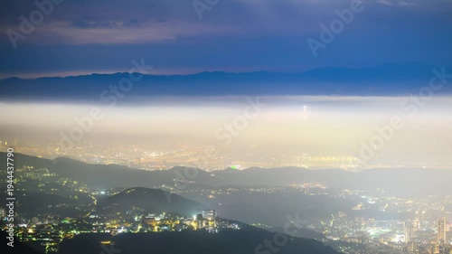 A stunning night view of Taipei city from Datun Mountain in Beitou, featuring glowing city lights shrouded in thick, ethereal fog and clouds.